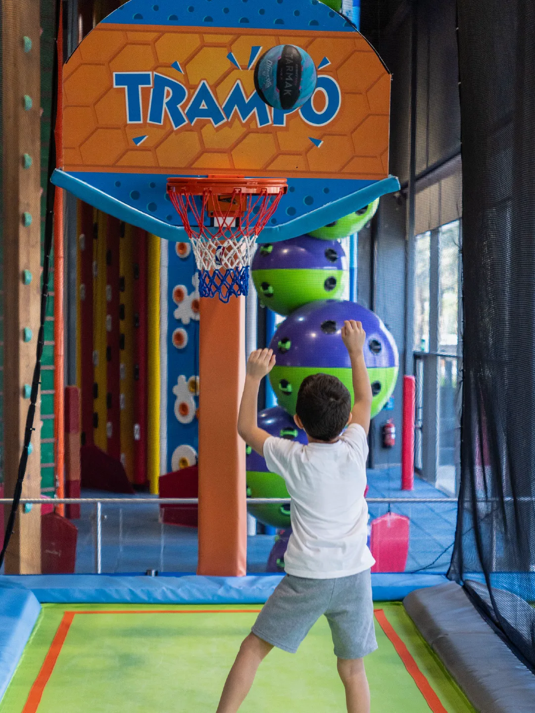 Boy reaching for a slam dunk on the trampoline basketball lane at Trampo Kuwait