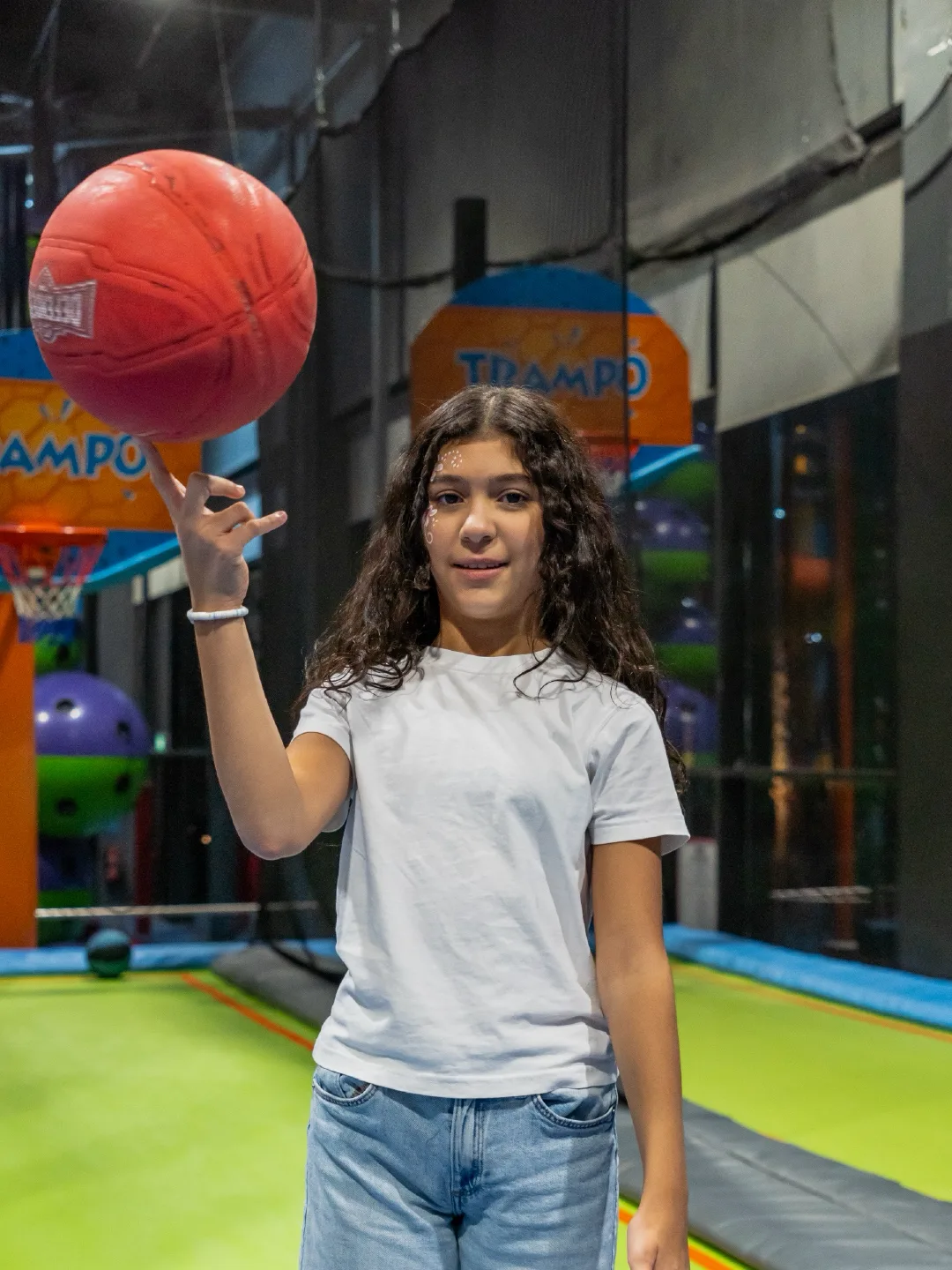 Girl spinning a basketball on her finger by the Trampo hoop at Trampo Kuwait