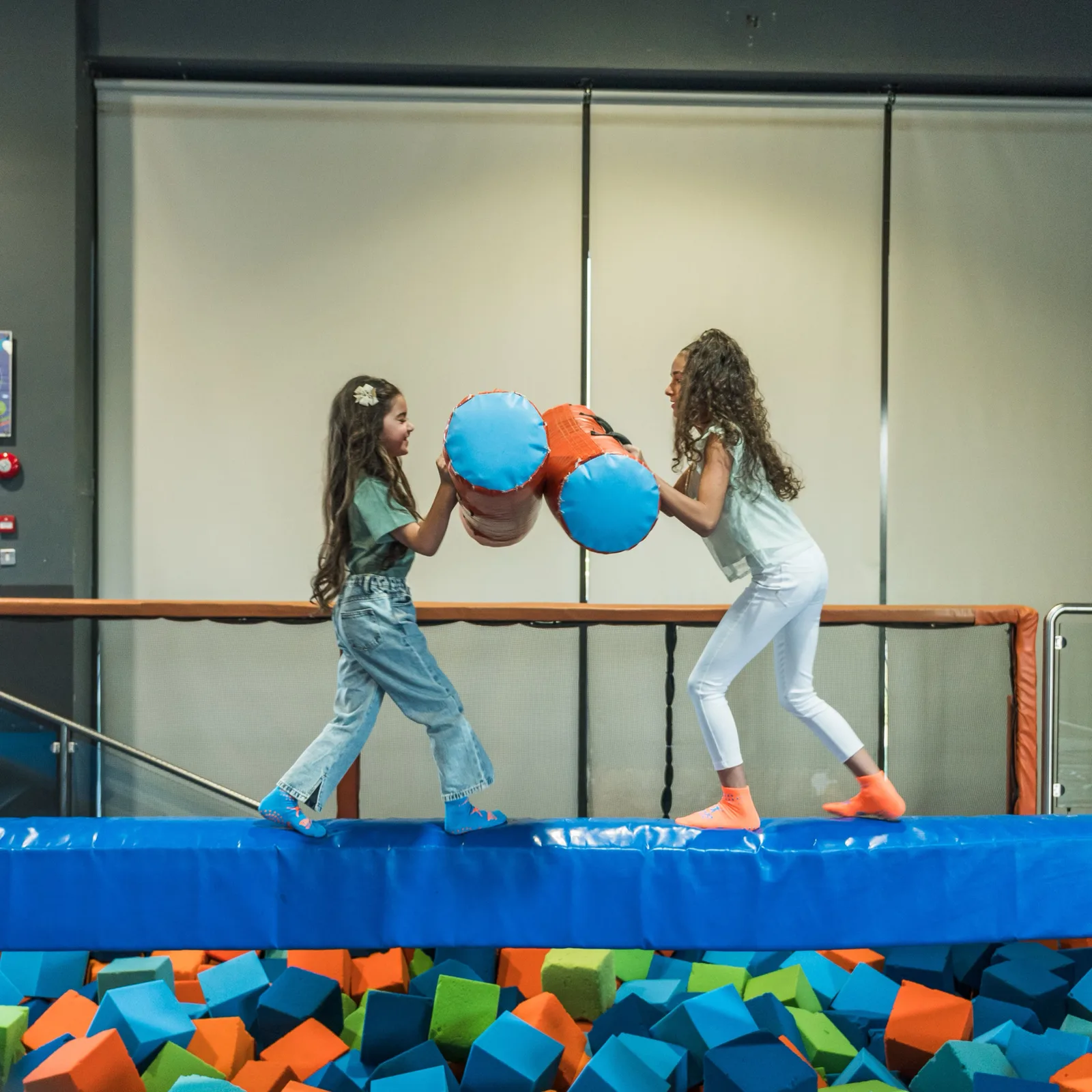Two girls battling on the padded beam at Trampo Kuwait