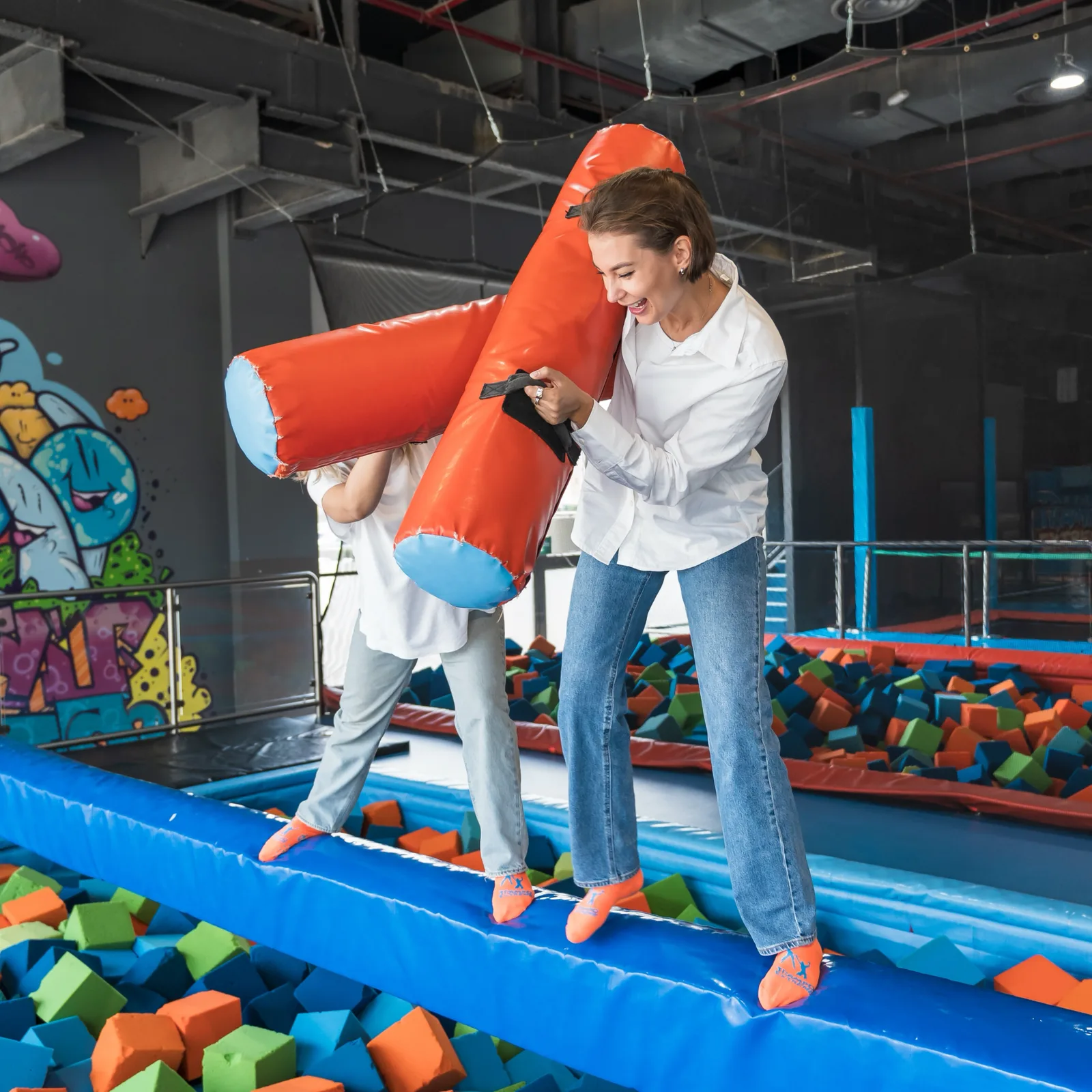 Parent and child laughing during a Battle Beam round at Trampo Kuwait