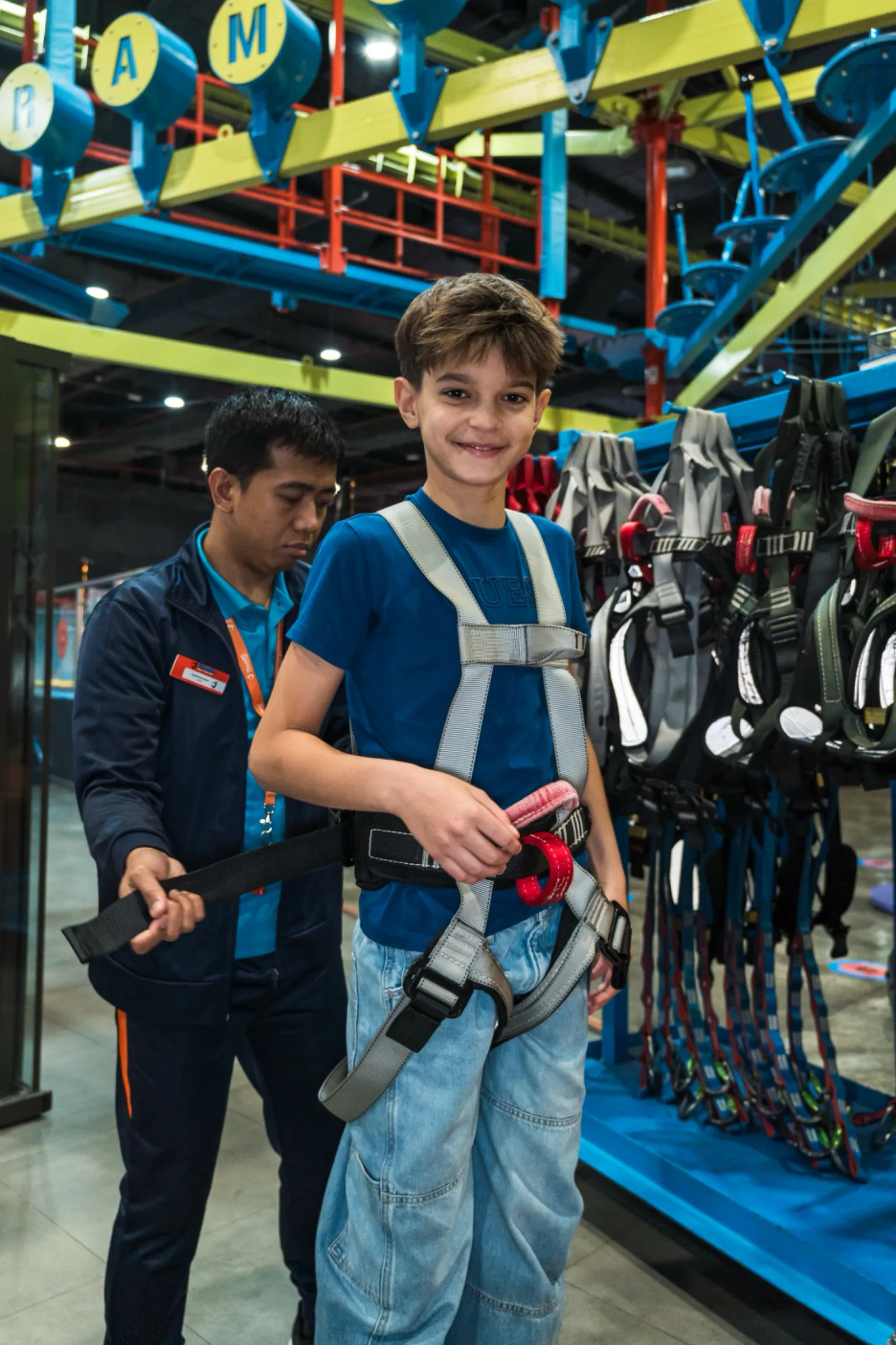Crew member helping a boy fit his harness before the Skytrail course