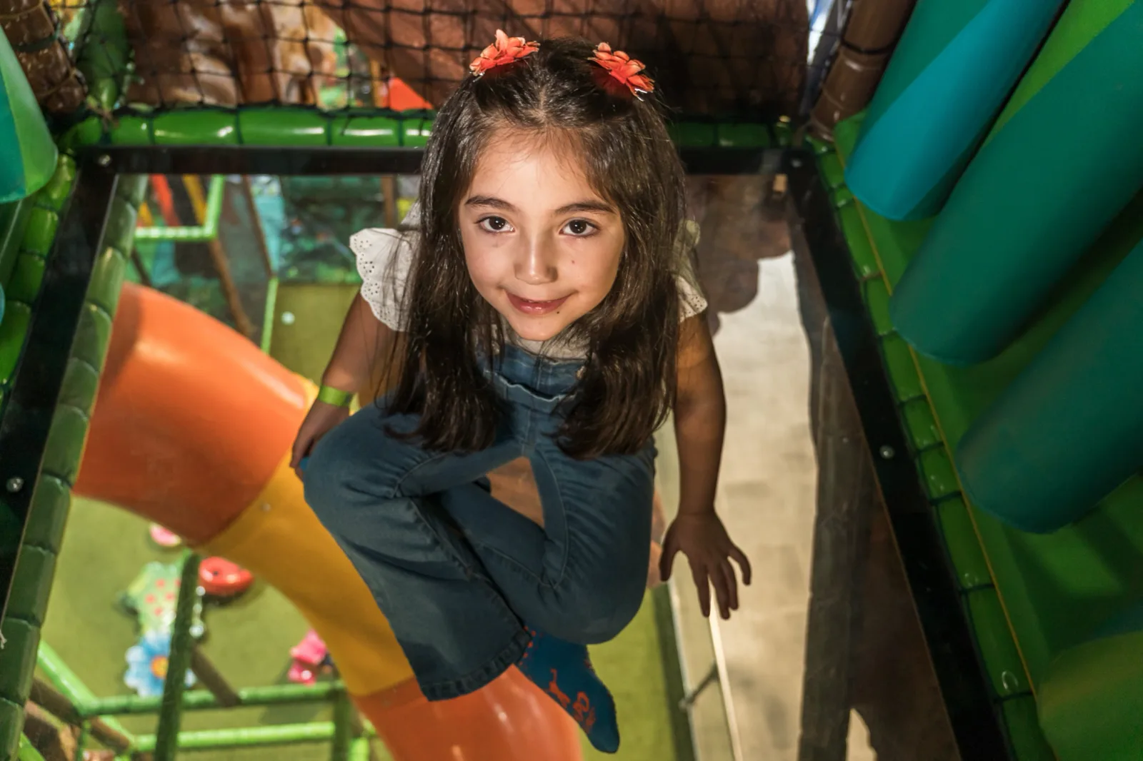 Smiling girl at the top of the slide inside the Soft Play tree house