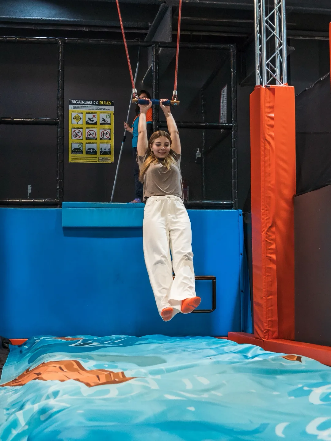 Teen gripping the trapeze bar above the BigAirBag landing at Trampo Kuwait Murouj