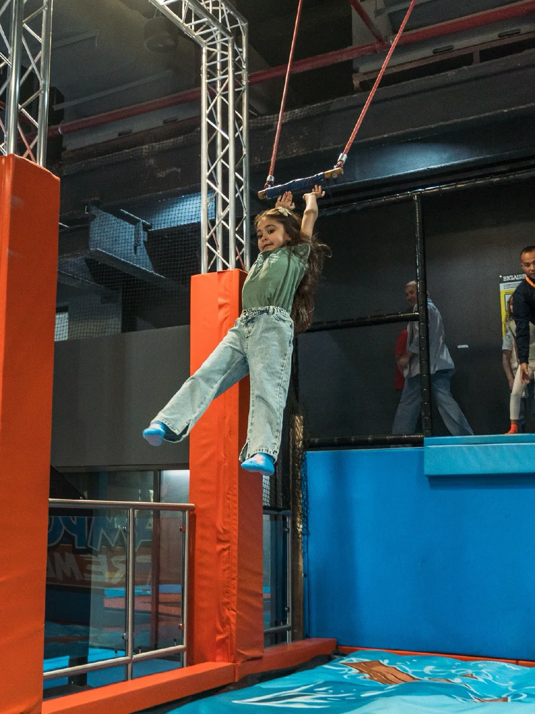 Girl swinging across on the trapeze bar at Trampo Kuwait Murouj