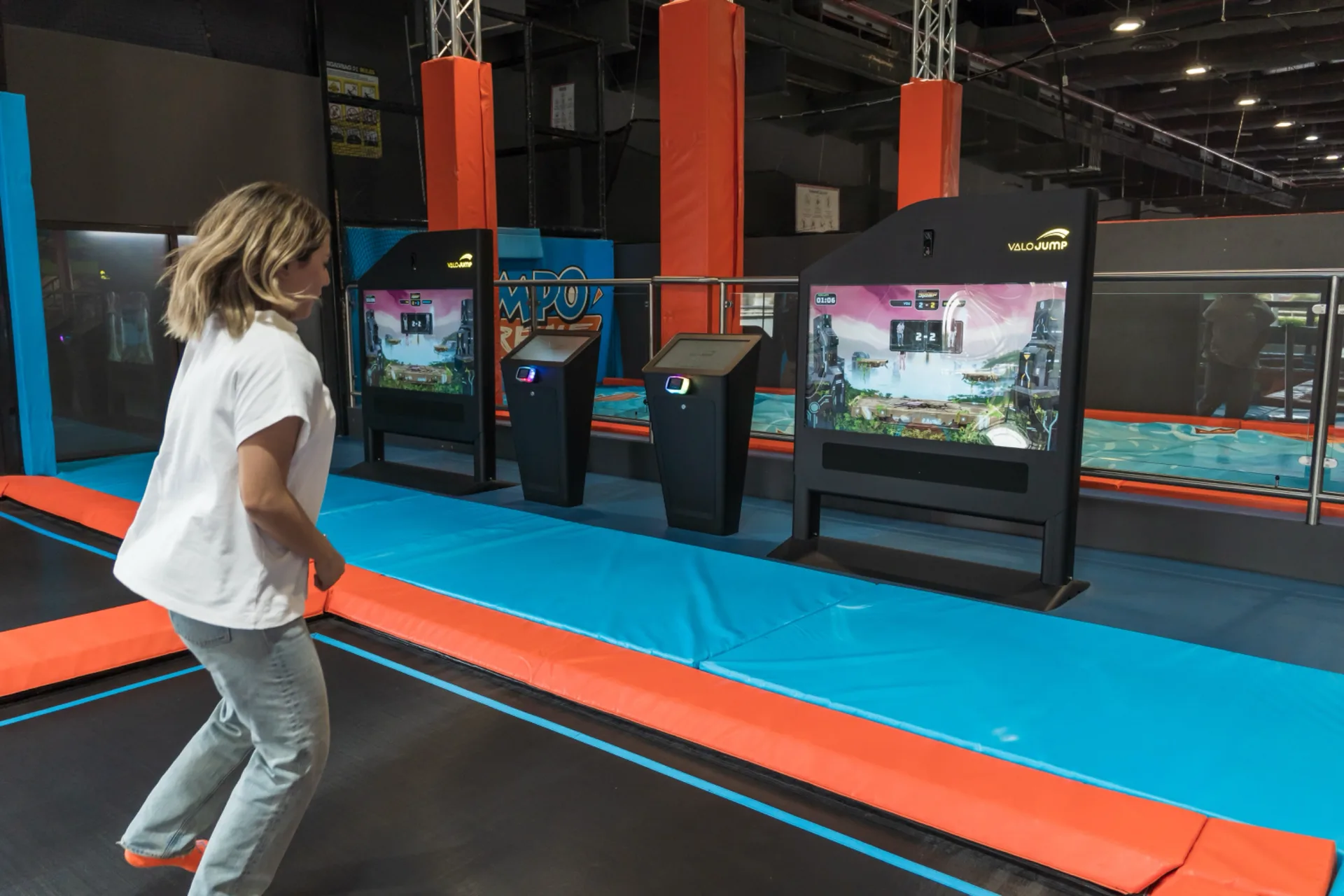 Player walking up to the twin Valo Jump screens and trampoline lanes at Trampo Kuwait Promenade