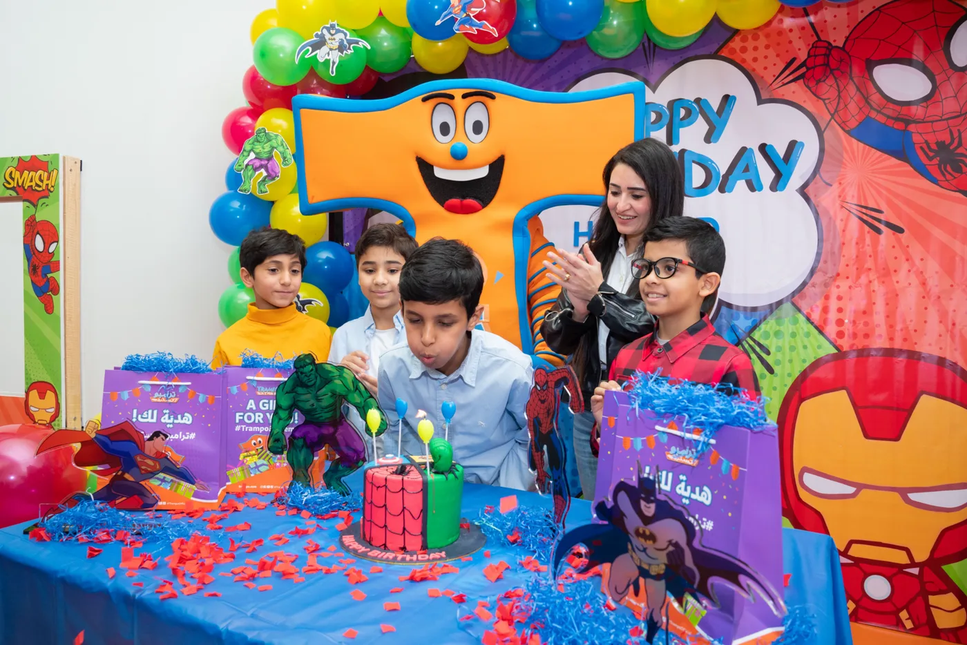 Boy blowing out candles at a superhero-themed birthday party