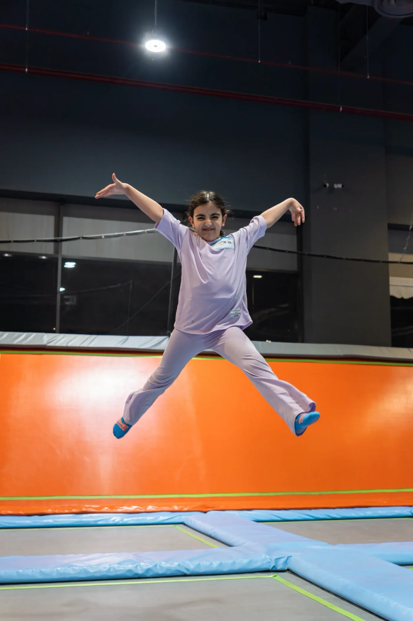 Girl mid-air in a starfish jump on the trampoline